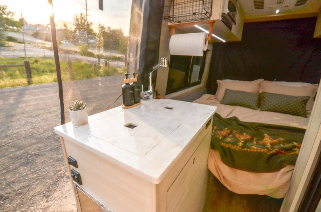 Galley island with sink and faucet, side door open to evening light