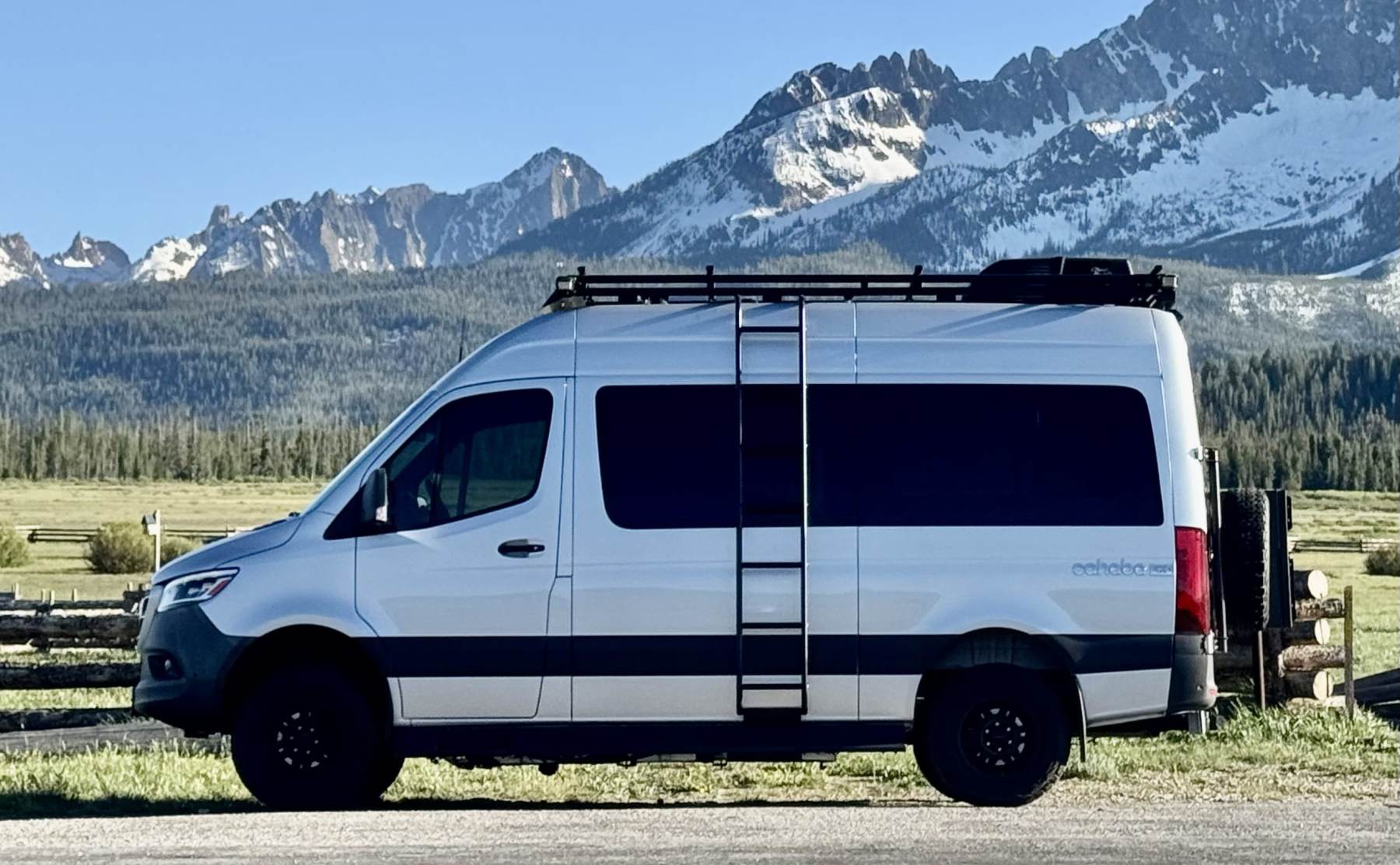 Roameo, a white 4x4 Sprinter camper van, parked below the snowy Sawtooth Mountains